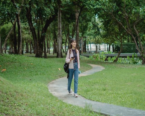 A person enjoying a peaceful morning walk in a green urban park in Indonesia