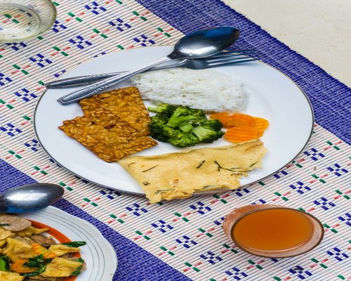 A healthy local Indonesian meal with vegetables, tofu, and a glass of water on a modern table